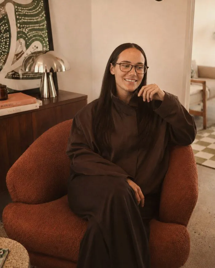 Lauren Lynch, founder of Queer Love Lounge, in a terracotta armchair